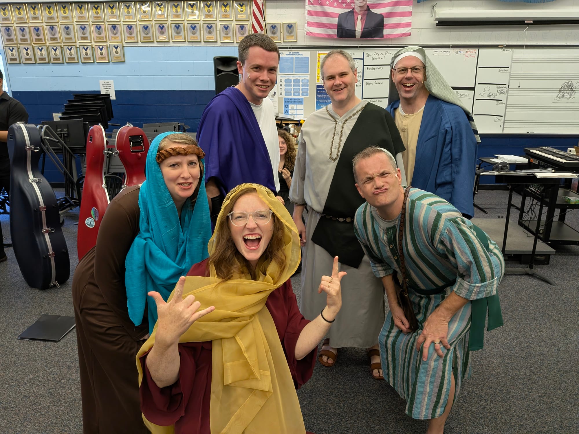 Cast members in costume laughing and posing together in a rehearsal room