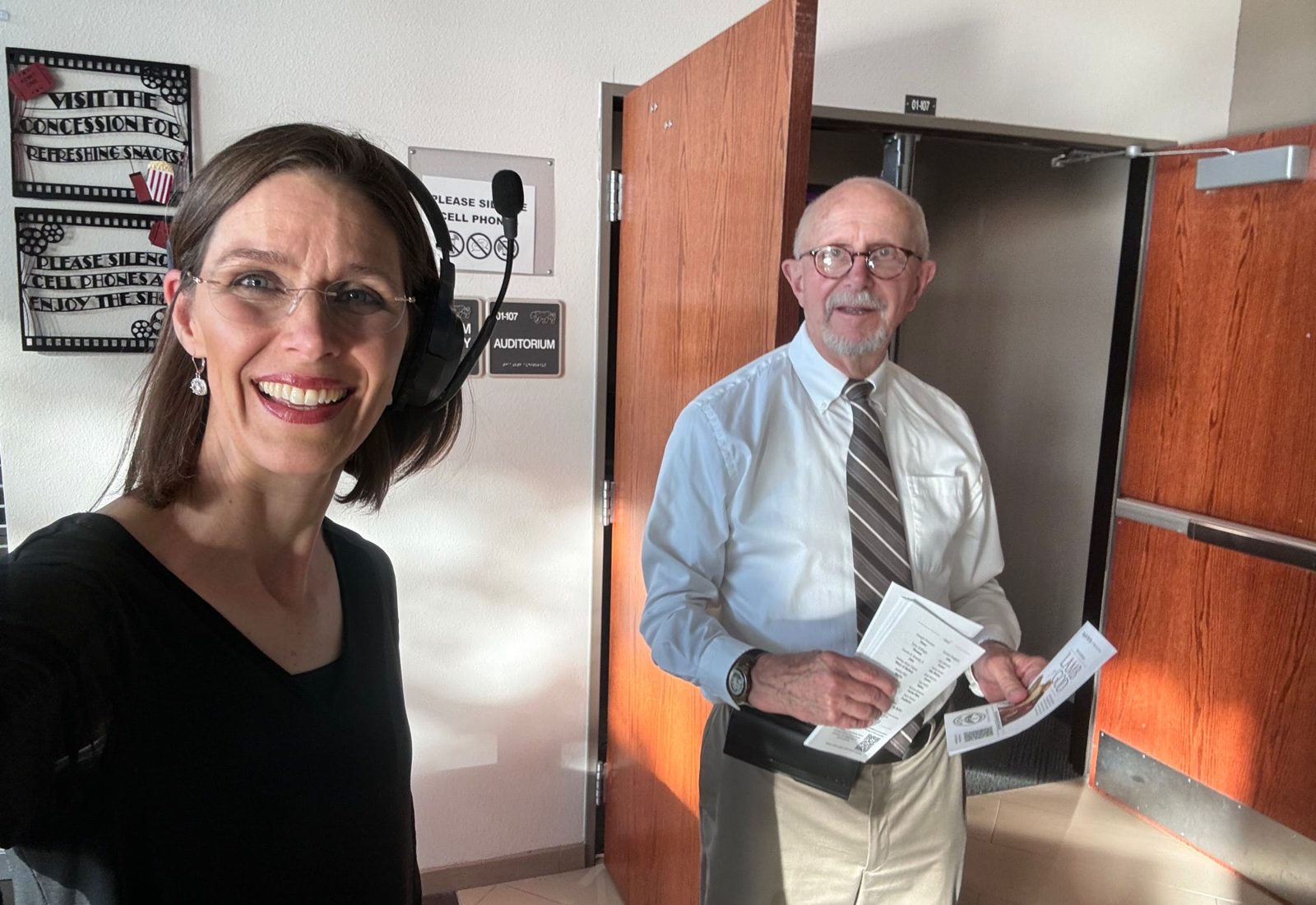 Two volunteers smiling outside the auditorium